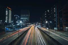 Cruce urbano al anochecer con los faros de los autos dejando estelas de luz